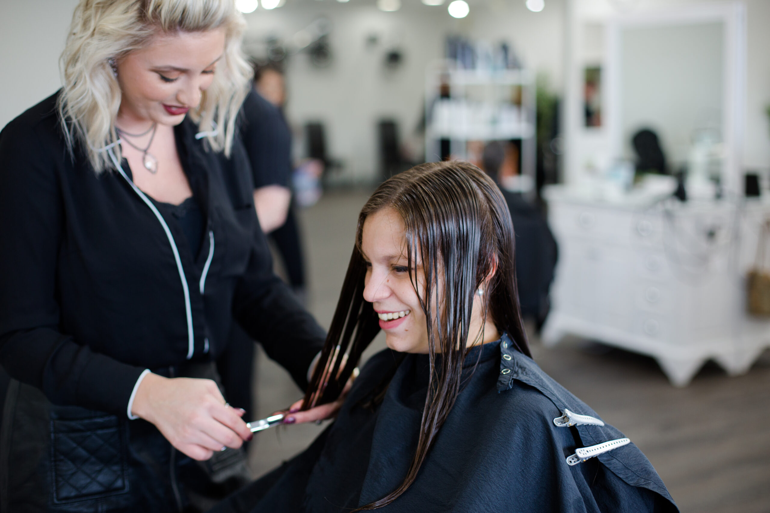 Hairdresser cutting a young woman's hair in a salon.