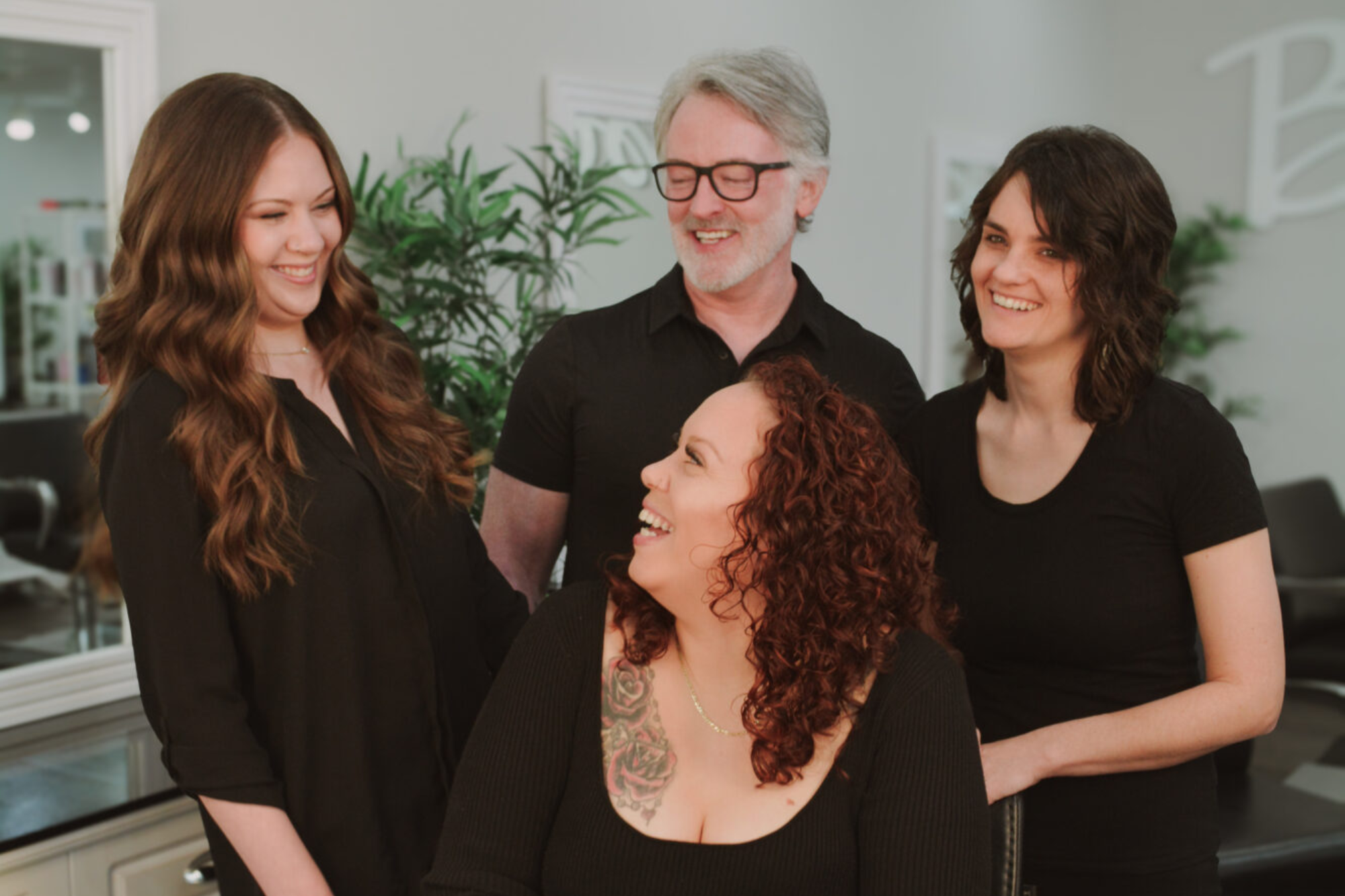Four adults smiling and interacting in a relaxed environment.