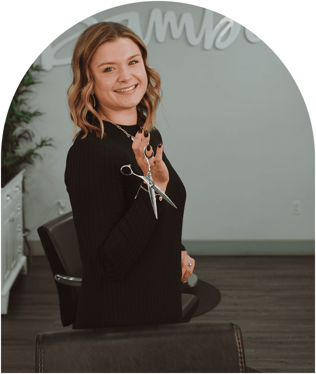 Woman smiling while sitting on a chair indoors, wearing a black outfit.