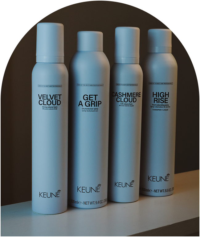 Four sleek silver hair product cans lined up on a wooden surface.