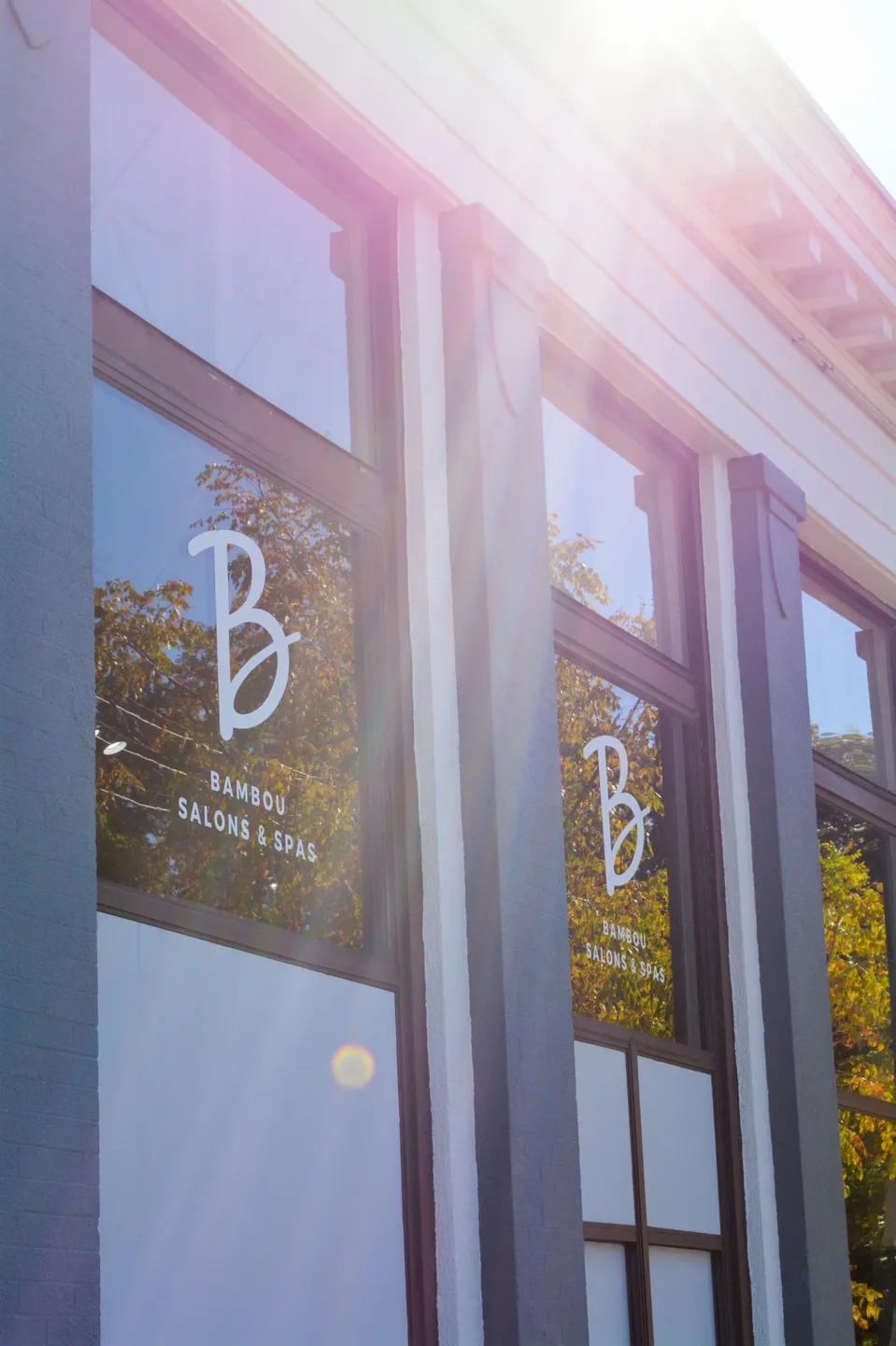 Sunlit storefront windows display elegant branding for a beauty salon.